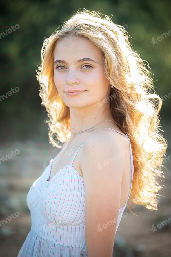 Blonde girl wearing a white dress photographed in a park in