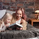 mom plays on the big bed in the bedroom with her daughter and reads a book to her mom plays on the big bed in the bedroom with her daughter and reads a book to her - PhotoDune Item for Sale