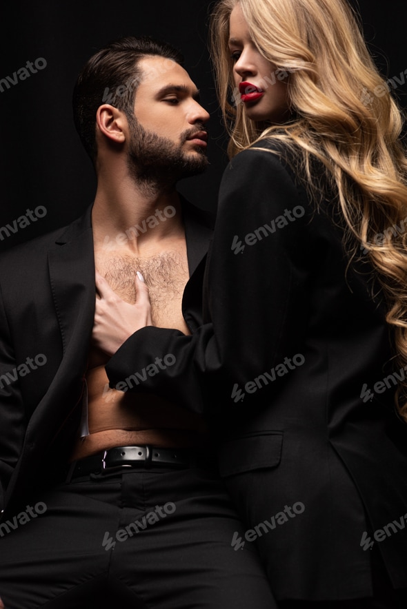 young woman touching sexy man in suit sitting on chair isolated on black Stock Photo by LightFieldStudios young woman touching sexy man in suit sitting on chair isolated on black Stock Photo by LightFieldStudios