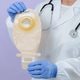An elderly doctor in a white coat holds a colostomy bag. An elderly doctor in a white coat holds a colostomy bag. - PhotoDune Item for Sale