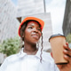 Happy black woman in helmet standing with coffee cup in daylight near buildings Happy black woman in helmet standing with coffee cup in daylight near buildings - PhotoDune Item for Sale