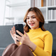 A woman is sitting on a couch and looking at her cell phone A woman is sitting on a couch and looking at her cell phone - PhotoDune Item for Sale
