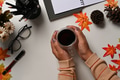 Overhead view woman holding coffee cup on white table with autumn maple leaves. Overhead view woman holding coffee cup on white table with autumn maple leaves. - PhotoDune Item for Sale