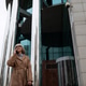 An elderly woman stands outside a modern glass building while talking on her mobile phone on a An elderly woman stands outside a modern glass building while talking on her mobile phone on a - PhotoDune Item for Sale