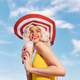 Young woman enjoying a cotton candy treat under a bright blue sky with fluffy white clouds, wearing Young woman enjoying a cotton candy treat under a bright blue sky with fluffy white clouds, wearing - PhotoDune Item for Sale