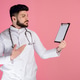 Young, male dctor, intern standing, looking aside, holding folder, raising hand, showing. Young, male dctor, intern standing, looking aside, holding folder, raising hand, showing. - PhotoDune Item for Sale