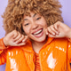 People and emotions concept. Positive curly haired woman smiles broadly keeps hands near face People and emotions concept. Positive curly haired woman smiles broadly keeps hands near face - PhotoDune Item for Sale