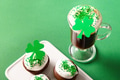 Irish coffee in green cup and festive cupcakes for St Patricks Day on green. Close up. Irish coffee in green cup and festive cupcakes for St Patricks Day on green. Close up. - PhotoDune Item for Sale