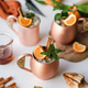 Alcohol cocktail drinks with tangerine and cinnamon in copper mugs Alcohol cocktail drinks with tangerine and cinnamon in copper mugs - PhotoDune Item for Sale