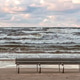 Empty beach chairs on Jurmala shore with waves crashing under cloudy sky Empty beach chairs on Jurmala shore with waves crashing under cloudy sky - PhotoDune Item for Sale