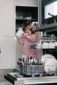 Cute toddler girl helps with cleaning, organizing in kitchen, empty dishwasher, geting utensils Cute toddler girl helps with cleaning, organizing in kitchen, empty dishwasher, geting utensils - PhotoDune Item for Sale