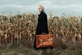 Stylish woman in black coat with suitcase in autumn corn field Stylish woman in black coat with suitcase in autumn corn field - PhotoDune Item for Sale