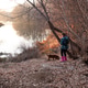 A young girl walks with her ginger dog along the river bank. Autumn landscape with river and sunset. A young girl walks with her ginger dog along the river bank. Autumn landscape with river and sunset. - PhotoDune Item for Sale