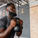 African American adult male holding kettlebell in goblet at warehouse gym wearing fitted gray tee African American adult male holding kettlebell in goblet at warehouse gym wearing fitted gray tee - PhotoDune Item for Sale