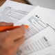 Person filling out a W-4 tax form with an orange pen, euros and a laptop on the side. Tax Person filling out a W-4 tax form with an orange pen, euros and a laptop on the side. Tax - PhotoDune Item for Sale