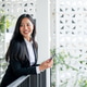 A beautiful, smiling Asian businesswoman stands on a building balcony with a smartphone in her hand. A beautiful, smiling Asian businesswoman stands on a building balcony with a smartphone in her hand. - PhotoDune Item for Sale
