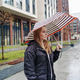 Walking pedestrian holds umbrella on rainy city street. Wet pavement commute, urban travel Walking pedestrian holds umbrella on rainy city street. Wet pavement commute, urban travel - PhotoDune Item for Sale