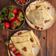 Crepes with chocolate hazelnut spread, strawberries and hazelnuts on a wooden table. Crepes with chocolate hazelnut spread, strawberries and hazelnuts on a wooden table. - PhotoDune Item for Sale