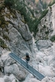 Woman standing on footbridge over mountain torrent, looking at landscape view Woman standing on footbridge over mountain torrent, looking at landscape view - PhotoDune Item for Sale