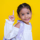 Smiling girl pointing up with finger on yellow background Smiling girl pointing up with finger on yellow background - PhotoDune Item for Sale