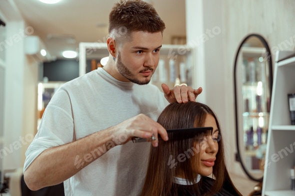 Professional male hairdresser making hairstyle to woman at beauty salon Stock Photo by astakhovyaroslav Professional male hairdresser making hairstyle to woman at beauty salon Stock Photo by astakhovyaroslav