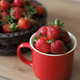 Ripe red strawberry in a mug and basket on the table Ripe red strawberry in a mug and basket on the table - PhotoDune Item for Sale