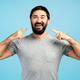 Smiling bearded man pointing his perfect white teeth with fingers on blue background Smiling bearded man pointing his perfect white teeth with fingers on blue background - PhotoDune Item for Sale
