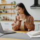 Asian businesswoman sitting with laptop in kitchen and enjoying cup of coffee. Asian businesswoman sitting with laptop in kitchen and enjoying cup of coffee. - PhotoDune Item for Sale