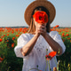 Young woman smelling poppy flower in poppy field wearing a straw hat Young woman smelling poppy flower in poppy field wearing a straw hat - PhotoDune Item for Sale
