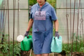 Mature woman with watering can gardening in greenhouse at home - shot in slow motion Mature woman with watering can gardening in greenhouse at home - shot in slow motion - PhotoDune Item for Sale