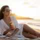 Elegant woman relaxing on tropical beach at sunset with cocktail drink Elegant woman relaxing on tropical beach at sunset with cocktail drink - PhotoDune Item for Sale
