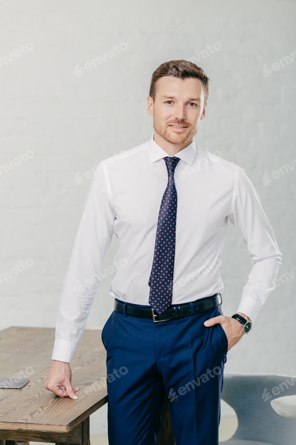 Attractive prosperous male in formal clothes, poses in office