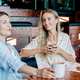 Two women friends sitting in a cafe talking and drinking coffee. Two women friends sitting in a cafe talking and drinking coffee. - PhotoDune Item for Sale