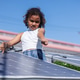 A playful young girl points while standing among solar panels under a bright blue sky A playful young girl points while standing among solar panels under a bright blue sky - PhotoDune Item for Sale