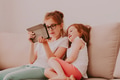 Video call with grandmother. Two little girls sitting on couch and using tablet pad. Cozy home Video call with grandmother. Two little girls sitting on couch and using tablet pad. Cozy home - PhotoDune Item for Sale