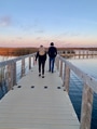 A blonde woman and dark haired man walk on a diminishing perspective boardwalk toward the ocean A blonde woman and dark haired man walk on a diminishing perspective boardwalk toward the ocean - PhotoDune Item for Sale