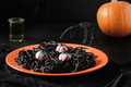 Halloween Italian black pasta decorated funny spiders in orange plate on black. Halloween Italian black pasta decorated funny spiders in orange plate on black. - PhotoDune Item for Sale