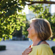 Senior woman with short gray hair wearing a yellow shirt stands outdoors Senior woman with short gray hair wearing a yellow shirt stands outdoors - PhotoDune Item for Sale