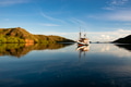 Sail boat reflection on the sea with mountain in the background Sail boat reflection on the sea with mountain in the background - PhotoDune Item for Sale