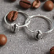 Silver Coffee Bean Rings on Gray Surface with Scattered Coffee Beans, Jewelry and Caffeine Concept. Silver Coffee Bean Rings on Gray Surface with Scattered Coffee Beans, Jewelry and Caffeine Concept. - PhotoDune Item for Sale