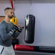 Indian man training in boxing area wearing fitted grey top, open-finger gloves near bags Indian man training in boxing area wearing fitted grey top, open-finger gloves near bags - PhotoDune Item for Sale