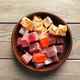 Assorted cubes of candy in a brown bowl on wooden table Assorted cubes of candy in a brown bowl on wooden table - PhotoDune Item for Sale