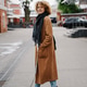 Stylish woman with curly hair walking in the city wearing a brown coat and jeans Stylish woman with curly hair walking in the city wearing a brown coat and jeans - PhotoDune Item for Sale