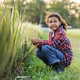 A young child crouches beside a rice field at sunset, gently touching the plants in warm light A young child crouches beside a rice field at sunset, gently touching the plants in warm light - PhotoDune Item for Sale