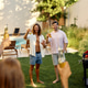 Friends raising bottled drinks at summer backyard barbecue by pool Friends raising bottled drinks at summer backyard barbecue by pool - PhotoDune Item for Sale