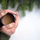 hands of an old man holding a cup of coffee on the background of a natural Christmas tree hands of an old man holding a cup of coffee on the background of a natural Christmas tree - PhotoDune Item for Sale
