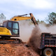 Excavator clearing debris loading it into dump truck during construction project in forest area Excavator clearing debris loading it into dump truck during construction project in forest area - PhotoDune Item for Sale