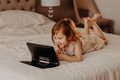 Toddler girl lying on bed in modern room, using laptop tablet pad gadget, watching with smiling face Toddler girl lying on bed in modern room, using laptop tablet pad gadget, watching with smiling face - PhotoDune Item for Sale