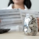 Savings concept coins in jar woman check expenses list with laptop Savings concept coins in jar woman check expenses list with laptop - PhotoDune Item for Sale