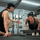 A focused and determined Asian woman is being trained by a fitness trainer while performing push-ups A focused and determined Asian woman is being trained by a fitness trainer while performing push-ups - PhotoDune Item for Sale